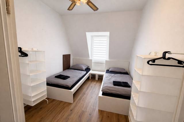 Schlafzimmer mit zwei getrennten Einzelbetten und Stoffregalen in einer Monteurwohnung in Frankfurt am Main