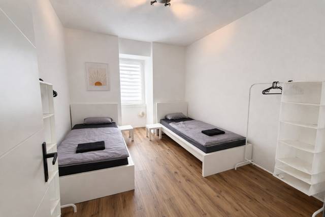 Schlafzimmer mit zwei Einzelbetten, Beistelltischen und Kleiderständer in der Monteurwohnung in Frankfurt am Main