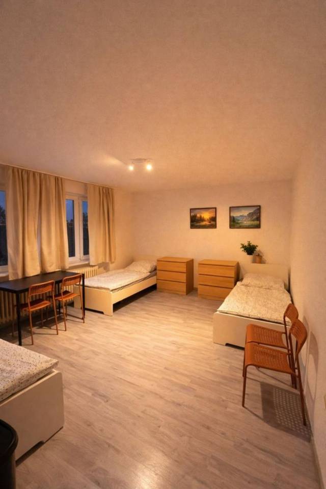 Schlafraum mit Betten, zwei Kommoden und Tisch mit Stühlen eines Monteurzimmers in Frankfurt am Main