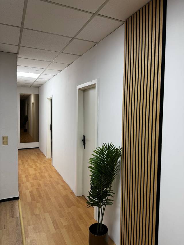 Flurabschnitt mit Laminatboden, Zimmertür und Wandspiegel in einer Monteurwohnung in Dreieich