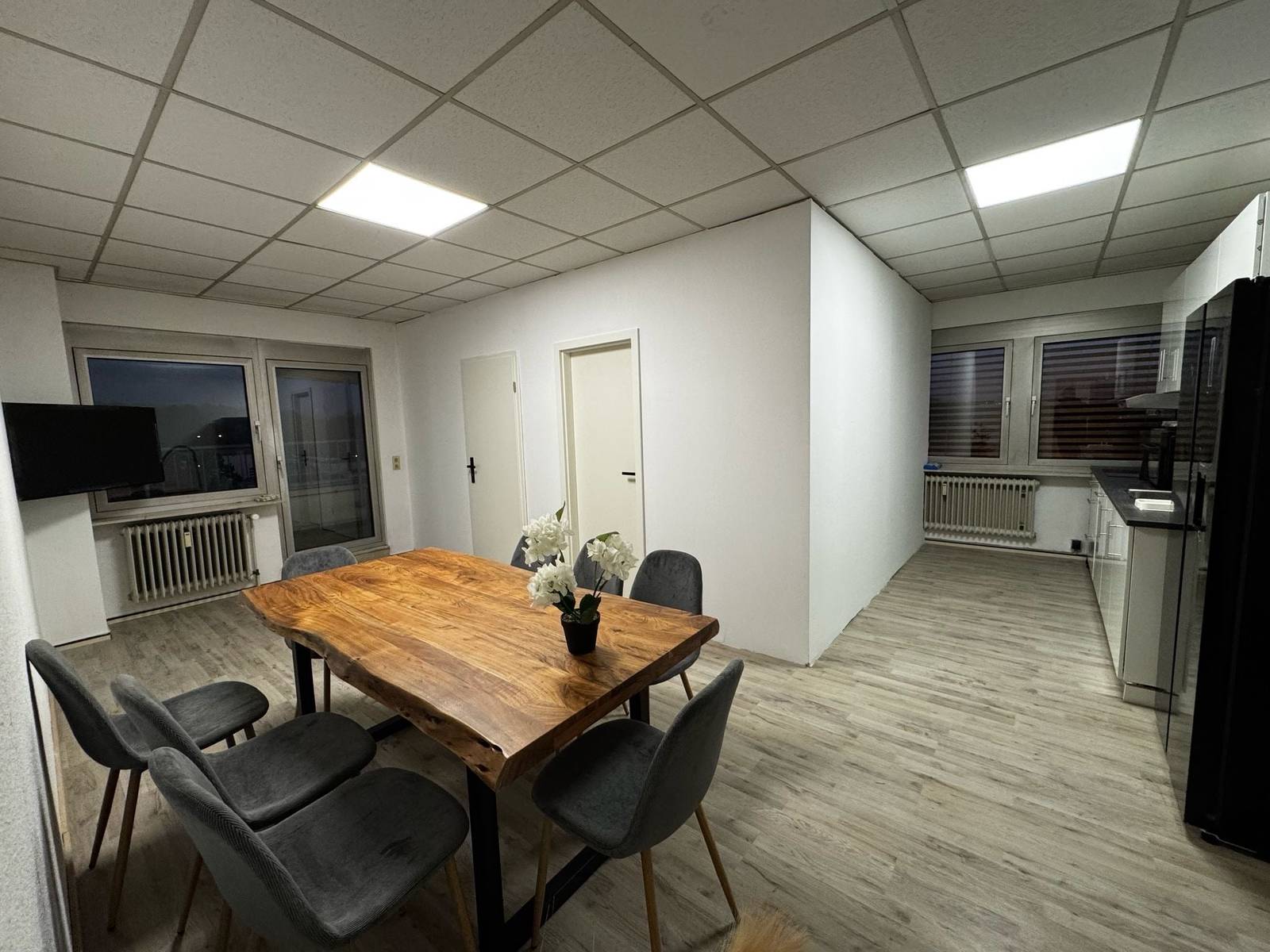 Holztisch mit grauen Stühlen und dahinter Küchenzeile in der Monteurwohnung in Dreieich