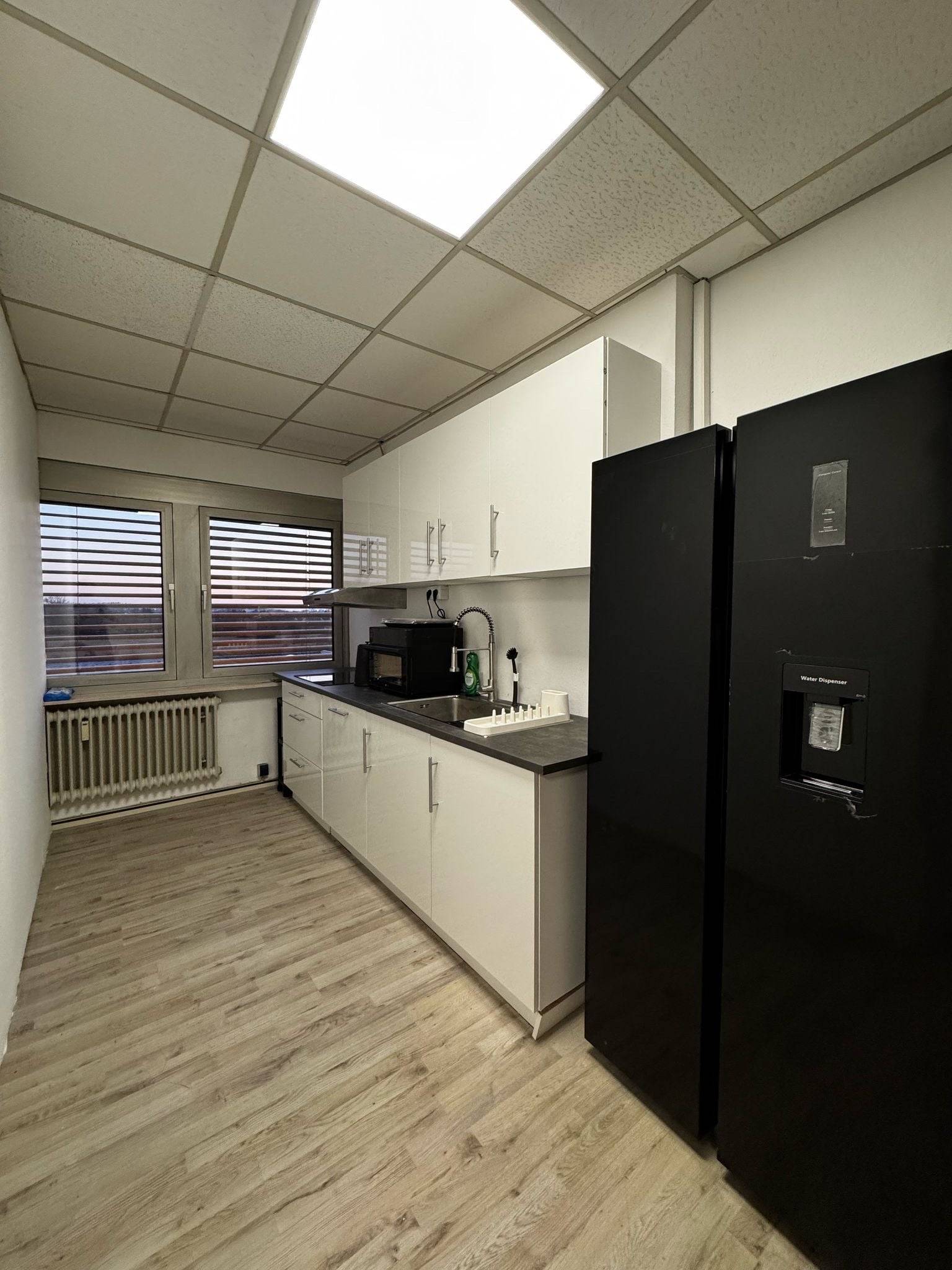 Küchenzeile mit Spüle, Mikrowelle und schwarzem Kühlschrank in der Monteurwohnung in Dreieich