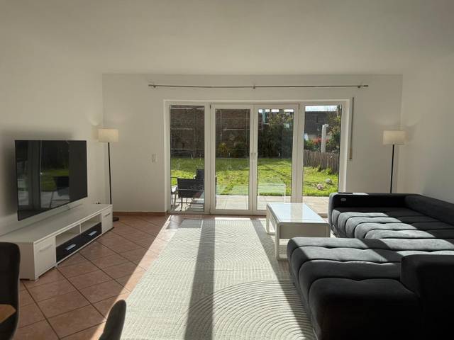 Sofa, Couchtisch und Fernseher vor der Terrassentür in der Monteurwohnung in Oestrich-Winkel