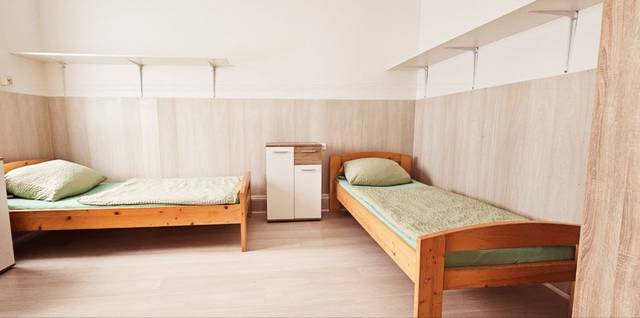Zwei getrennte Holzbetten mit Kommode und Wandregalen in einer Monteurwohnung in Frankfurt am Main