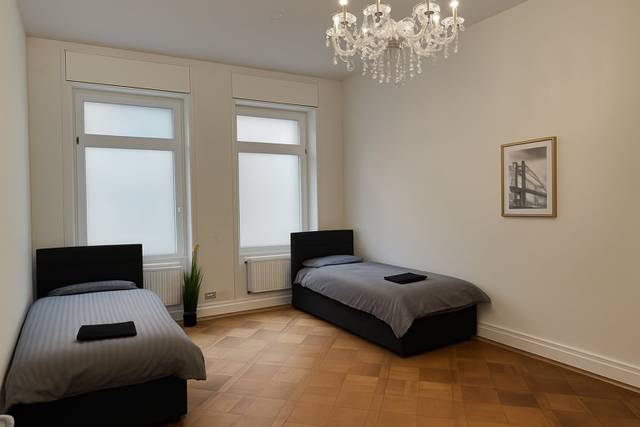 Schlafzimmer mit zwei getrennten Einzelbetten und Kronleuchter in einer Monteurwohnung in Offenbach am Main