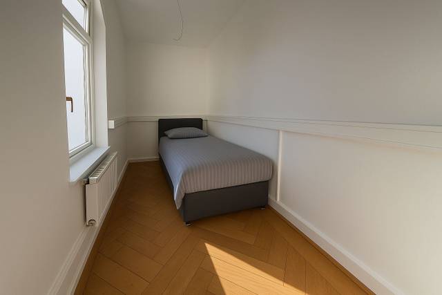 Schmales Zimmer mit einem Einzelbett und Heizkörper in der Monteurwohnung in Offenbach am Main
