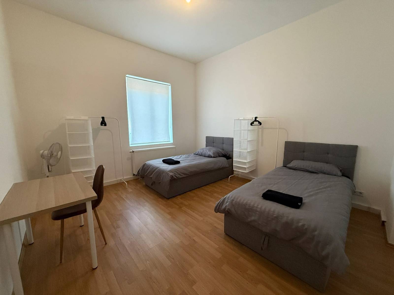 Zwei getrennte Einzelbetten, Tisch und Stuhl in einem Zimmer der Monteurwohnung in Frankfurt am Main