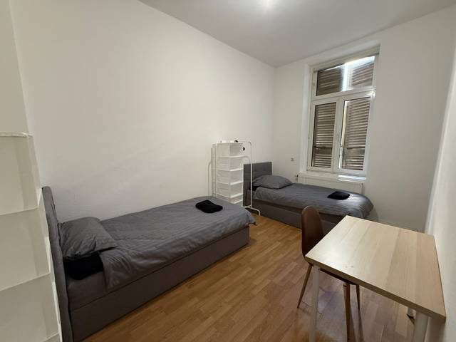 Zwei Einzelbetten und ein Tisch mit Stuhl in einer Monteurwohnung in Frankfurt am Main