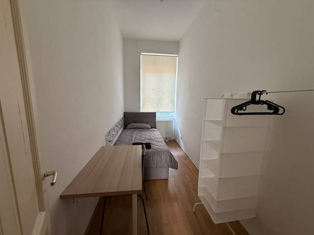 Schmales Zimmer mit Einzelbett, Tisch und Hängeregal in der Monteurwohnung in Frankfurt am Main