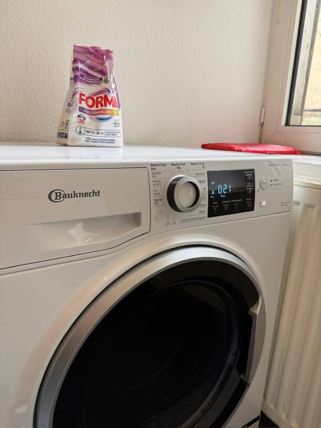 Weiße Bauknecht Waschmaschine mit Waschmittelpackung darauf in der Monteurwohnung in Frankfurt am Main