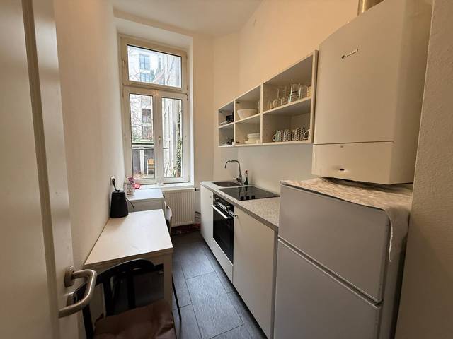 Schmale Küche mit Herd, Backofen, Kühlschrank und Tisch in einer Monteurwohnung in Frankfurt am Main