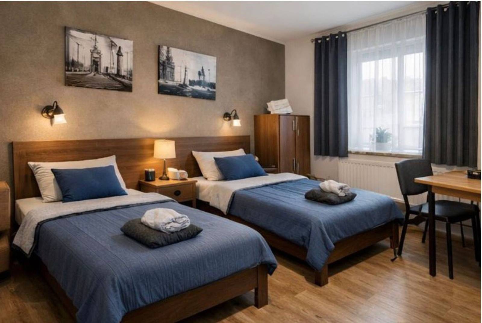 Zwei getrennte Einzelbetten mit Nachttisch, Schrank und Tisch in einer Monteurwohnung in Frankfurt am Main