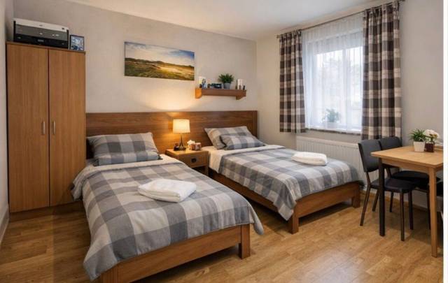 Schlafzimmer mit zwei getrennten Einzelbetten, Kleiderschrank und Esstisch in der Monteurwohnung in Frankfurt am Main