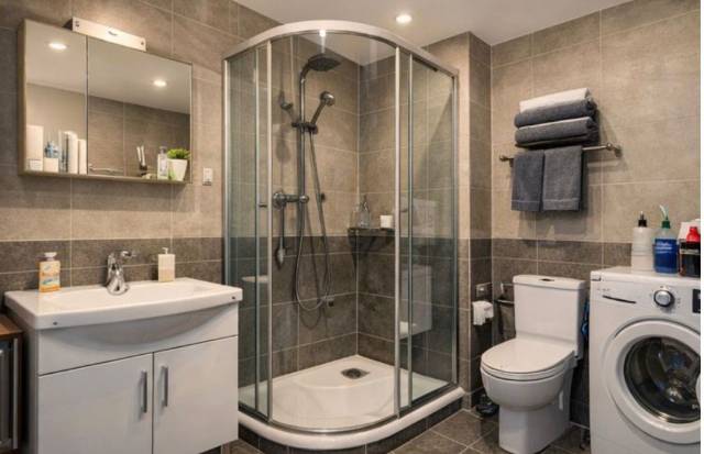 Badezimmer mit Duschkabine, Waschbecken, WC und Waschmaschine in einer Monteurwohnung in Frankfurt am Main