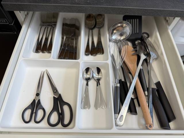 Offene Schublade mit sortiertem Besteck, Scheren und Küchenhelfern in der Monteurwohnung in Frankfurt am Main