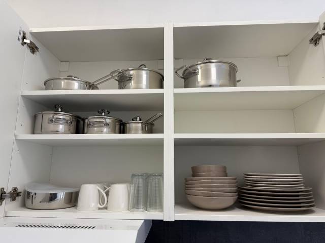 Offener Hängeschrank mit Töpfen, Tellern, Schalen und Tassen in der Monteurwohnung in Frankfurt am Main