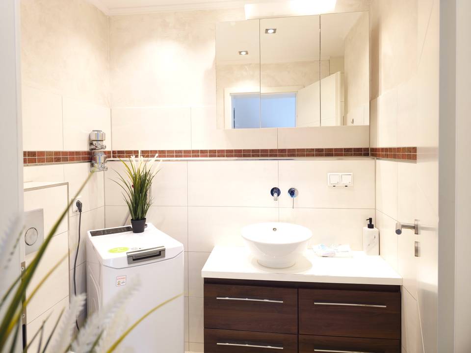 Badezimmer mit Waschbecken, Spiegelschrank und Waschmaschine in der Monteurwohnung in Hanau