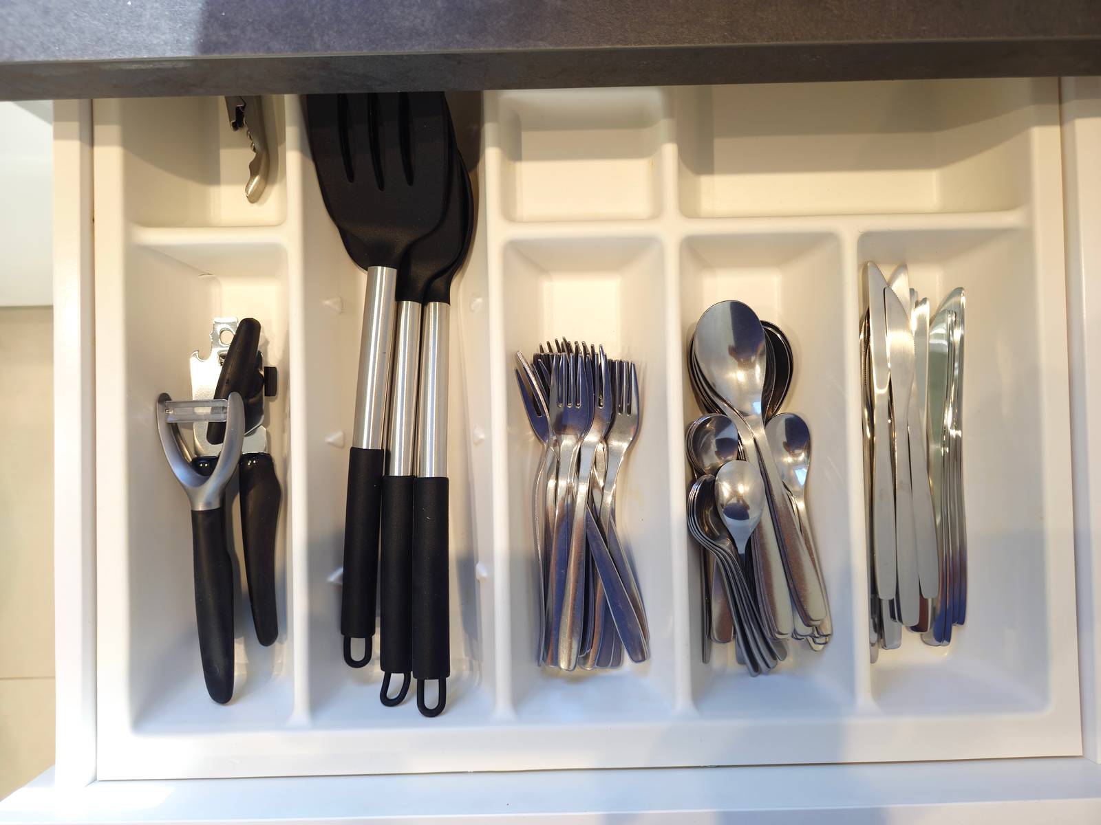 Geöffnete Schublade mit Gabeln, Löffeln, Messern und Küchenhelfern in der Monteurwohnung in Hanau
