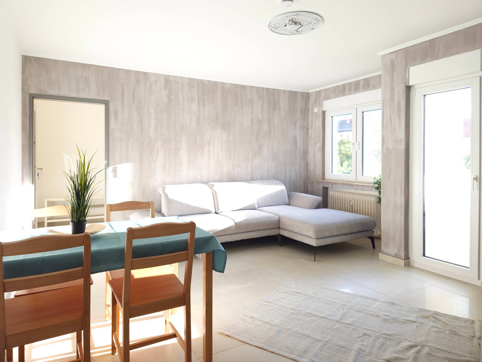 Wohnraum mit Ecksofa, Esstisch mit Stühlen und Balkontür in der Monteurwohnung in Hanau