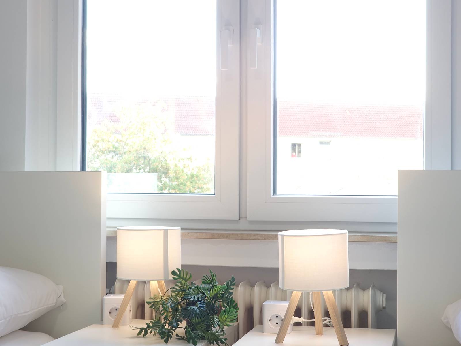 Zwei Nachttische mit Lampen und Steckdosenwürfeln am Fenster in der Monteurwohnung in Hanau