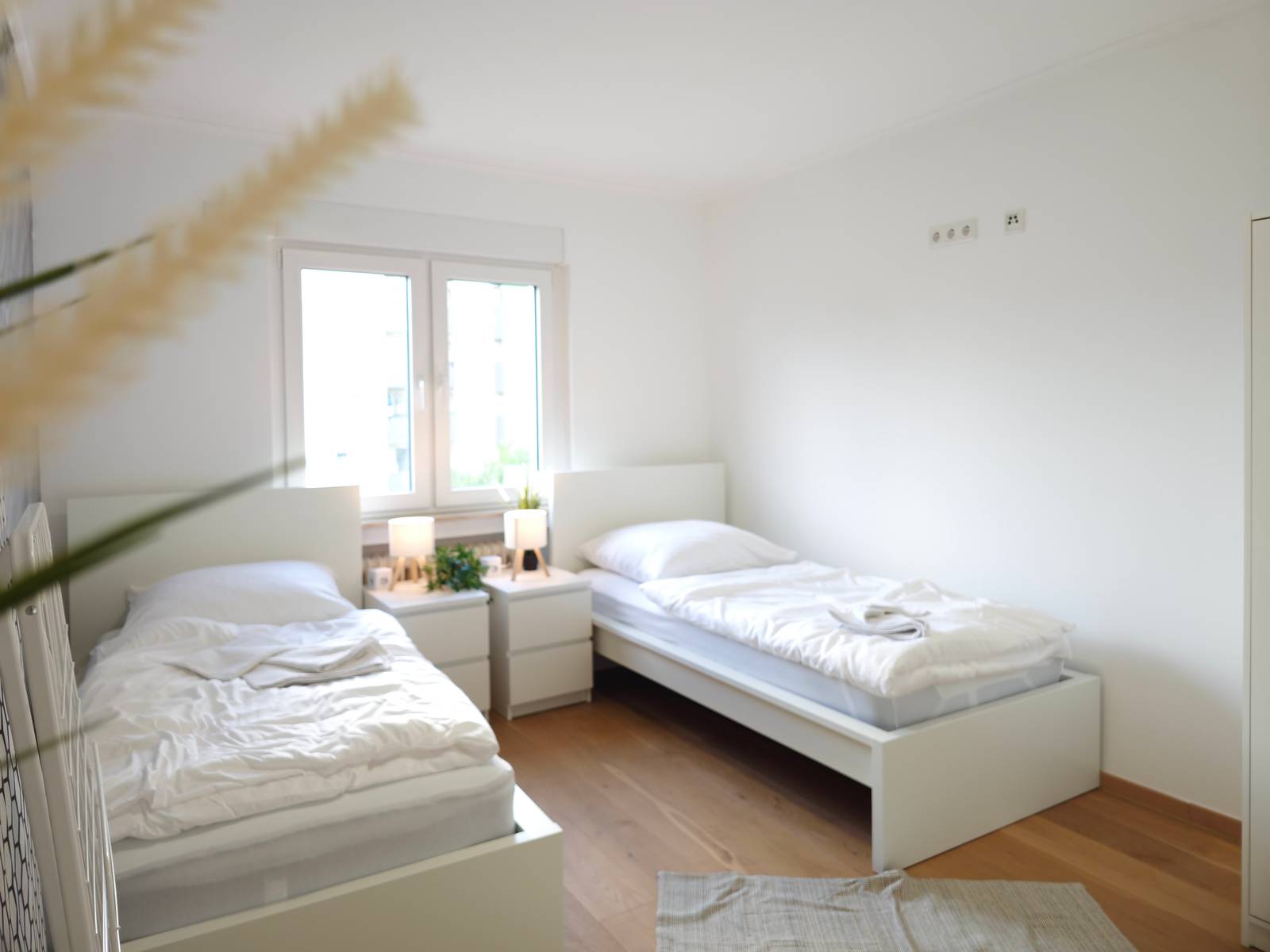 Zwei Einzelbetten mit Nachttischen am Fenster in der Monteurwohnung in Hanau