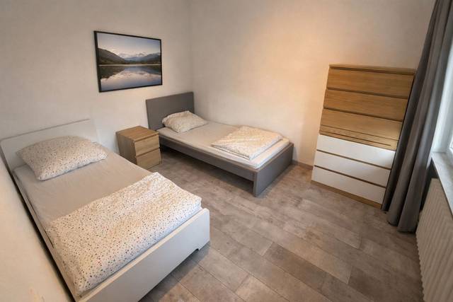 Zwei getrennte Einzelbetten und eine hohe Kommode in einem Schlafzimmer eines Monteurzimmers in Rüsselsheim
