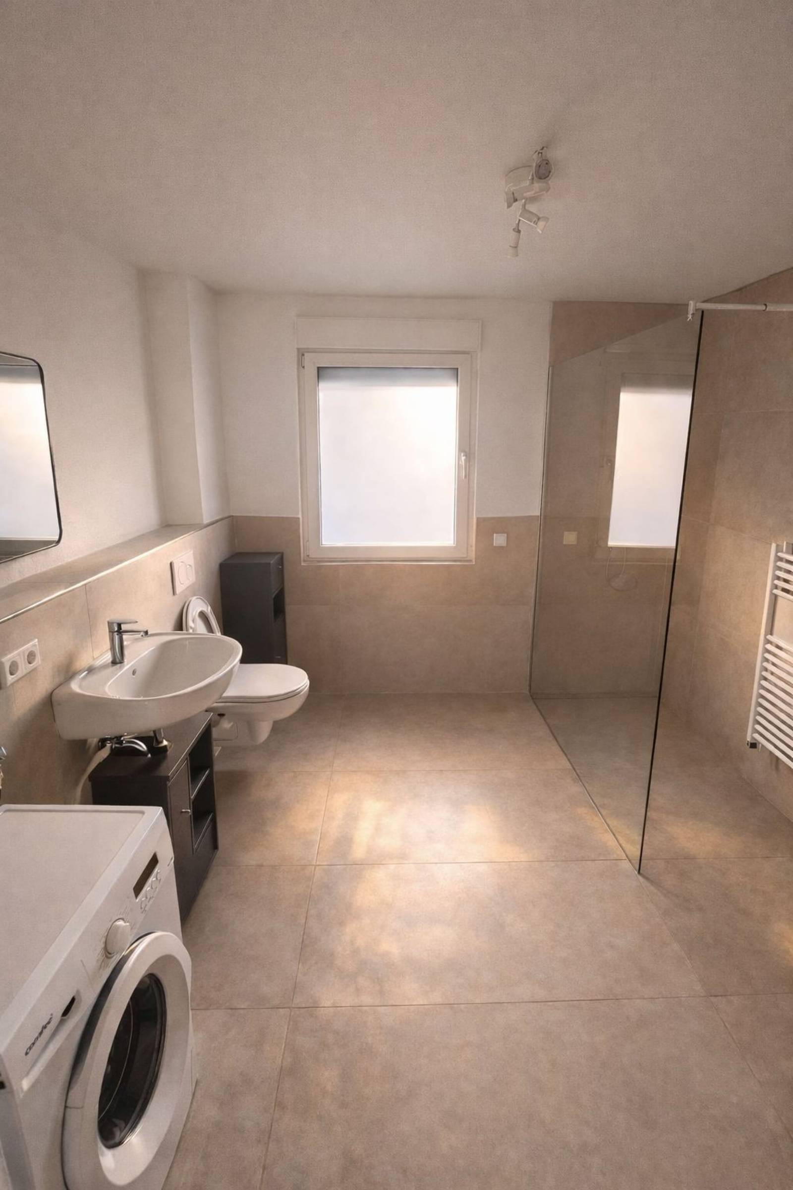 Badezimmer mit bodenebener Glasdusche, Waschbecken, WC und Waschmaschine in der Monteurzimmer in Rüsselsheim