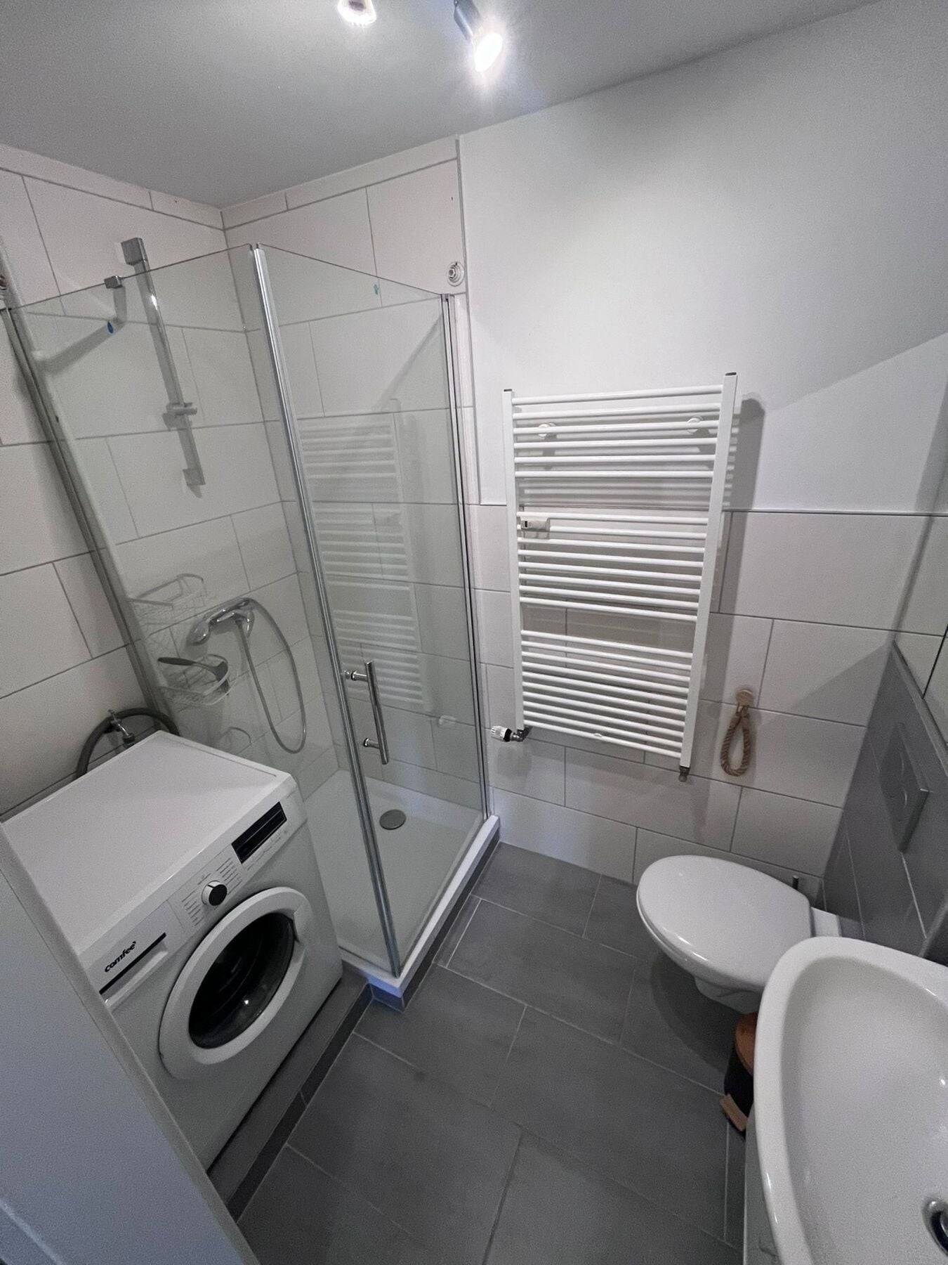 Bad mit Duschkabine, Handtuchheizkörper, WC und Waschmaschine in der Monteurzimmer in Rüsselsheim