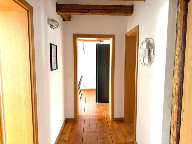 Flur mit Holzdielen und offener Tür zum Raum mit Kühlschrank in der Monteurwohnung in Offenbach am Main