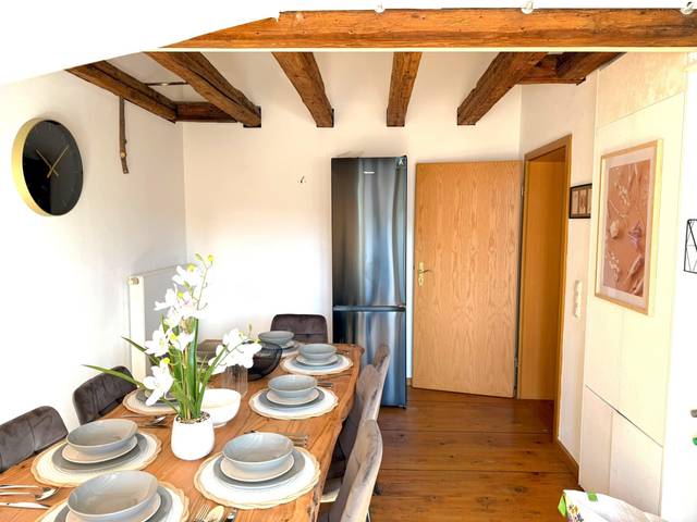 Gedeckter Holztisch mit Stühlen und Kühlschrank im Hintergrund in der Monteurwohnung in Offenbach am Main