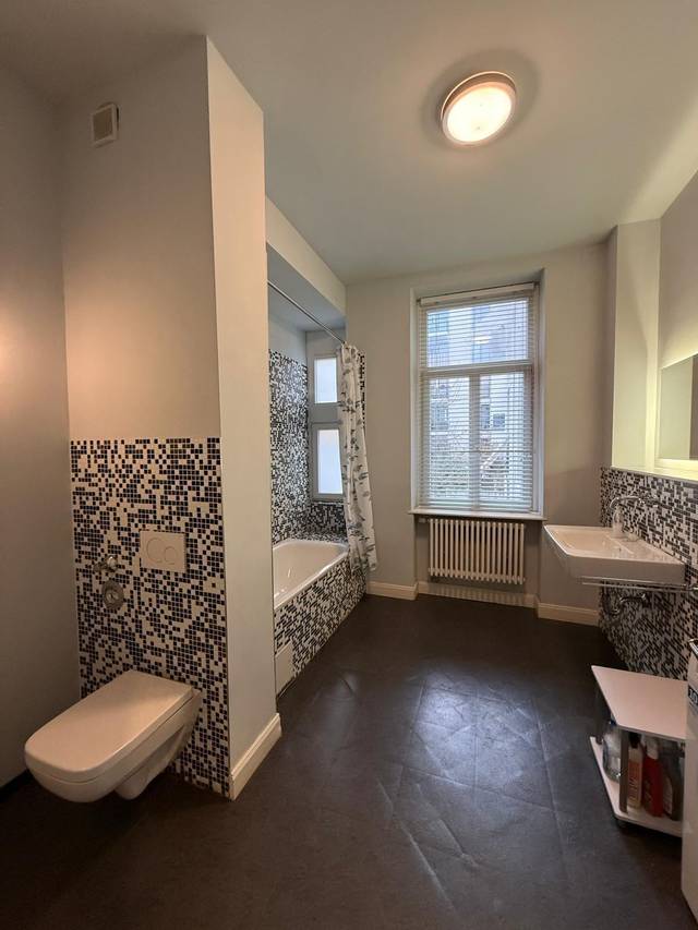 Gesamtansicht des Bads mit Wanne, Wand-WC, Waschbecken und Heizkörper in der Monteurwohnung in Frankfurt am Main