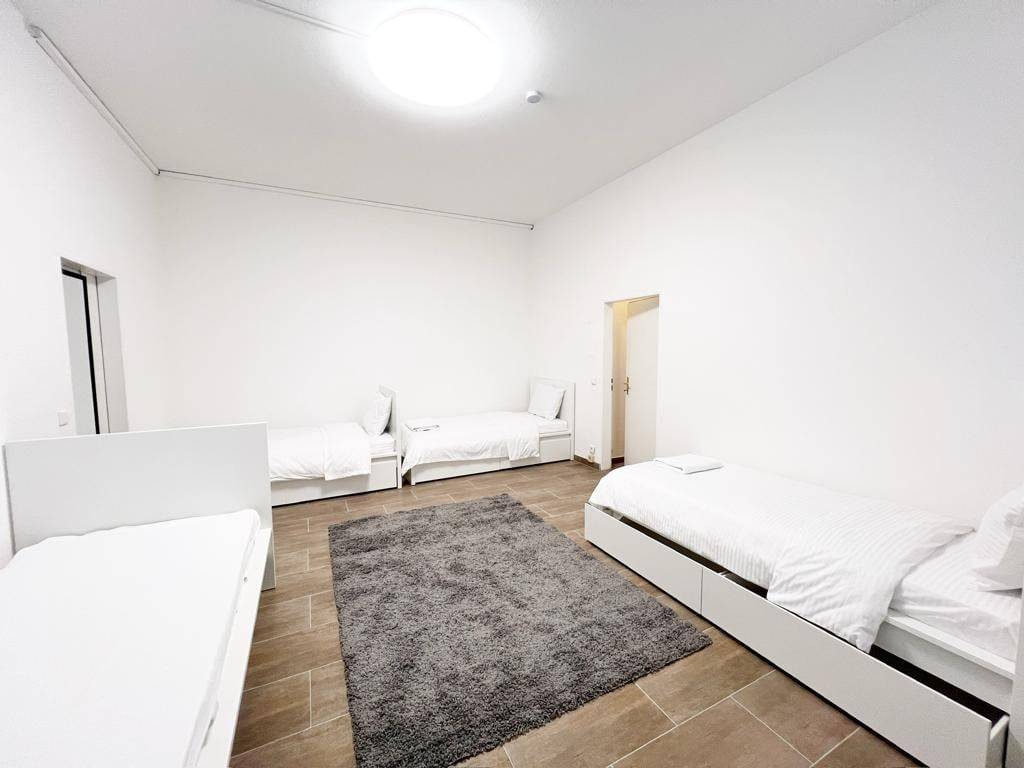 Vier getrennte Einzelbetten mit weißer Bettwäsche und Teppich in der Monteurwohnung in Wiesbaden
