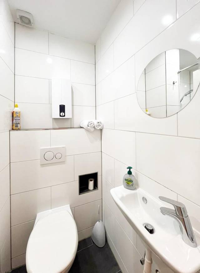 Wandhängendes WC, Handwaschbecken und runder Spiegel im Bad der Monteurwohnung in Wiesbaden