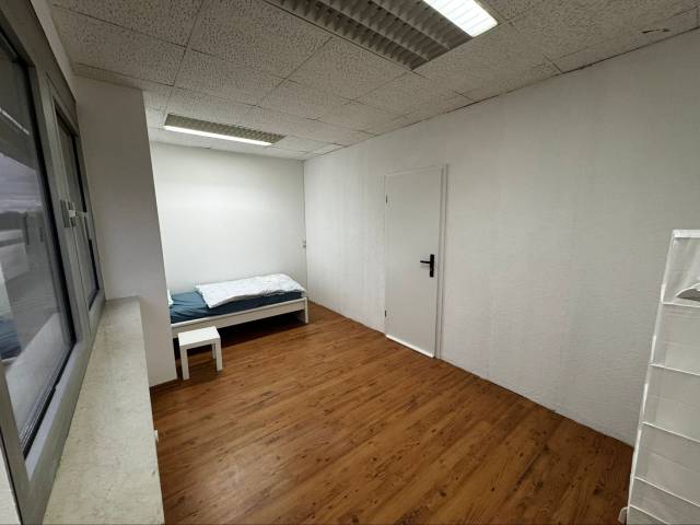 Zimmer mit Einzelbett, weißem Beistelltisch und Tür in der Monteurwohnung in Frankfurt am Main