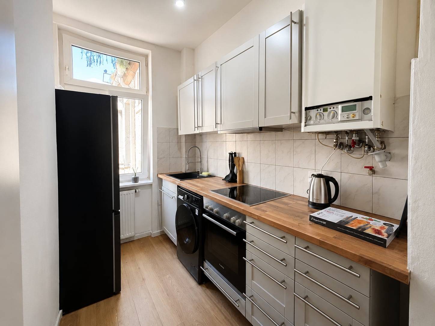 Küchenzeile mit Backofen, Kochfeld, Waschmaschine und Kühlschrank in der Monteurwohnung in Frankfurt am Main