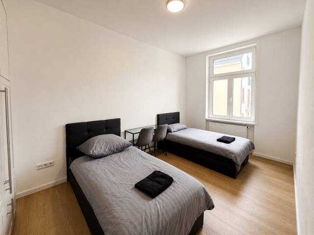 Schlafzimmer mit zwei Einzelbetten, Tisch und zwei Stühlen in einer Monteurwohnung in Frankfurt am Main