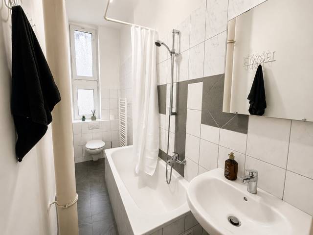 Badezimmer mit Badewanne, Duschvorhang, WC und Waschbecken in der Monteurwohnung in Frankfurt am Main