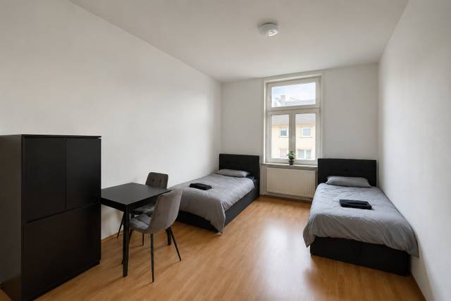 Zwei Einzelbetten, Tisch mit zwei Stühlen und Schrank in einer Monteurwohnung in Frankfurt am Main