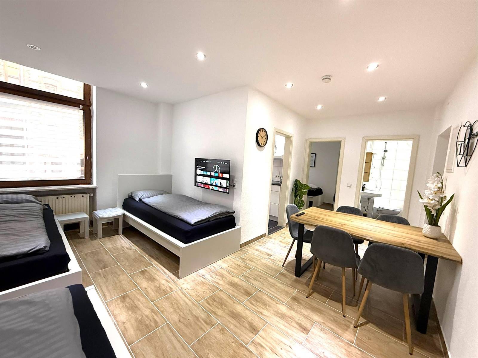 Einzelbetten, Esstisch mit vier Stühlen und Wand-TV in der Monteurwohnung in Wiesbaden