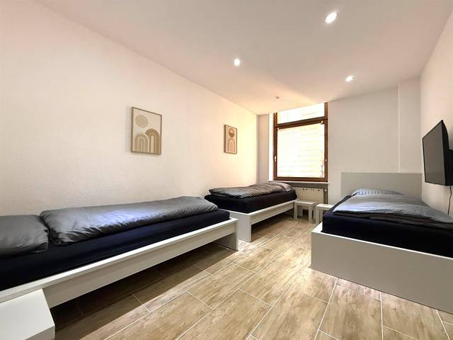 Drei getrennte Einzelbetten und ein Wand-TV in einem Zimmer der Monteurwohnung in Wiesbaden