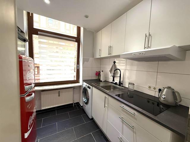 Küchenzeile mit Kochfeld, Spüle, Waschmaschine und rotem Kühlschrank in der Monteurwohnung in Wiesbaden