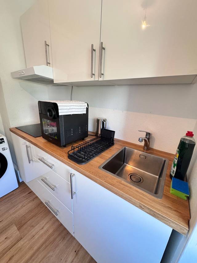 Küchenzeile mit Edelstahlspüle, Kochfeld und Wasserkocher in der Monteurwohnung in Mainz