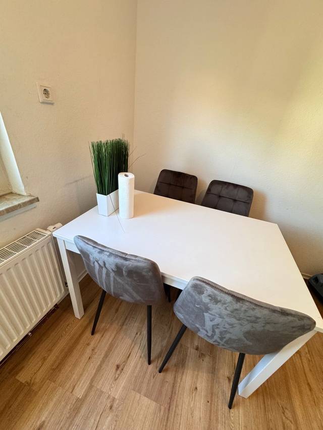 Weißer Esstisch mit vier gepolsterten Stühlen in einer Monteurwohnung in Mainz