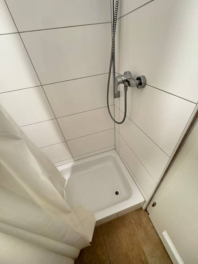 Geflieste Dusche mit Duschwanne und Vorhang in der Monteurwohnung in Mainz