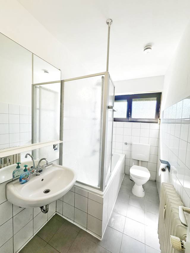 Badezimmer mit Badewanne, Duschwand, Waschbecken und WC in der Monteurwohnung in Niedernhausen