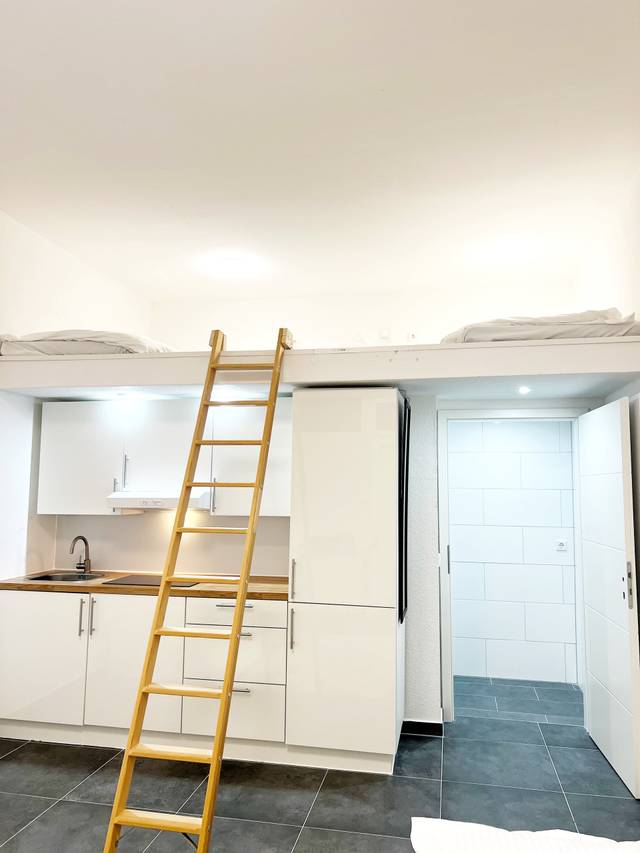 Küchenzeile mit Kühlschrank, Holzleiter und Hochebene mit Matratzen in der Monteurwohnung in Walluf