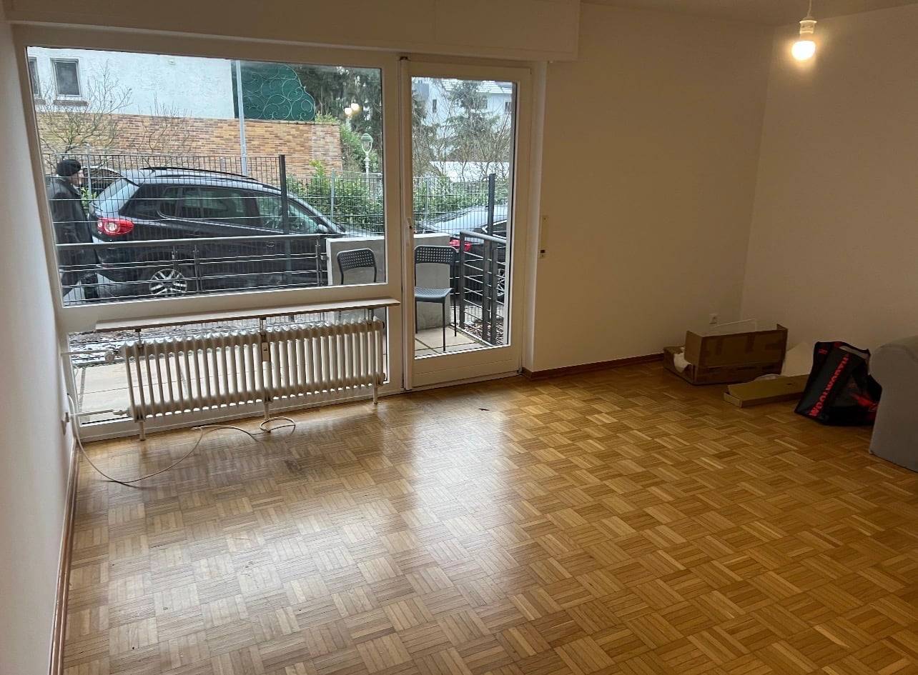 Raum mit Parkettboden, Heizkörper und Balkontür zu zwei Stühlen in der Monteurwohnung in Frankfurt am Main